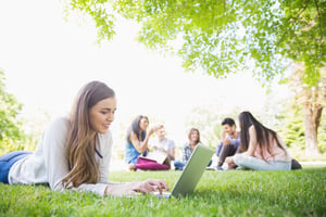 Happy student using her laptop outside at the university